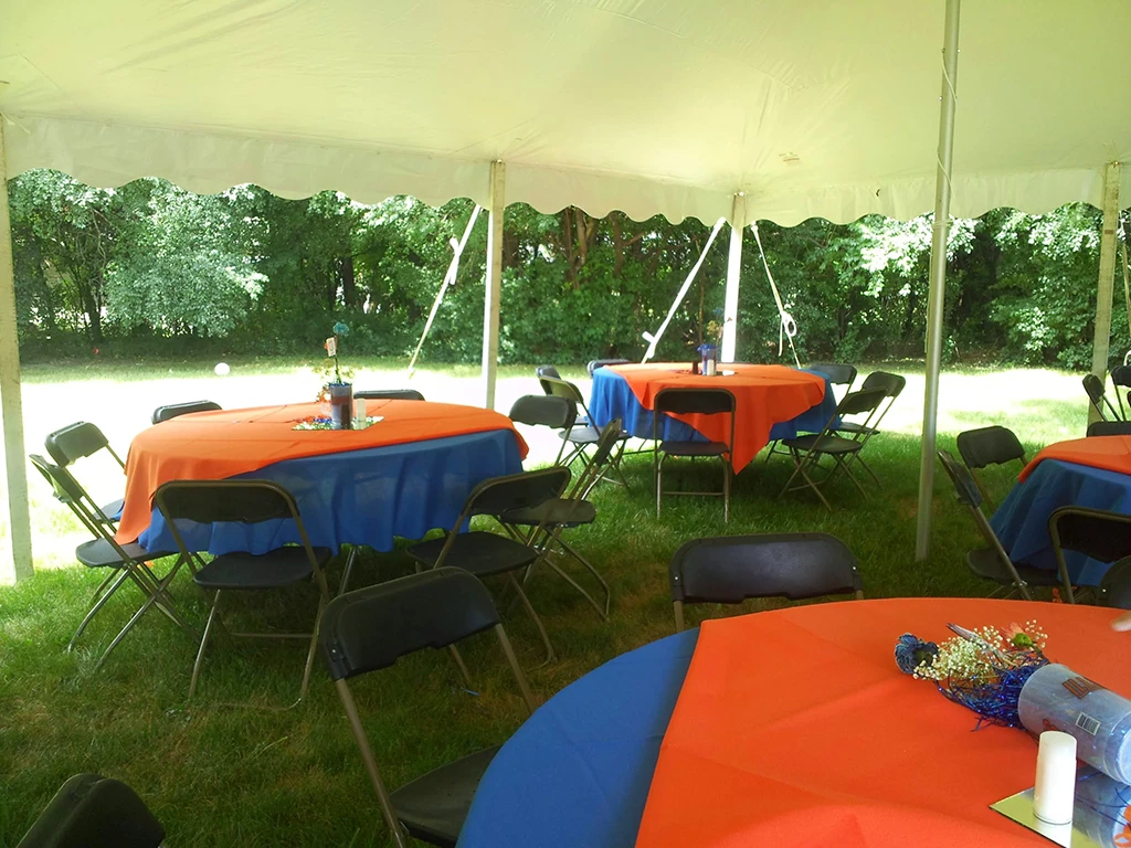 Tent interior with colorful tables, tiki torches, and party decorations