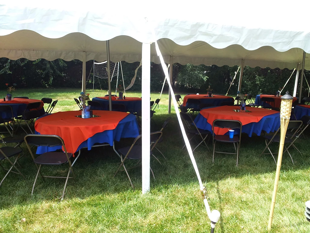Outdoor event setup with round tables in a tent using bright linens