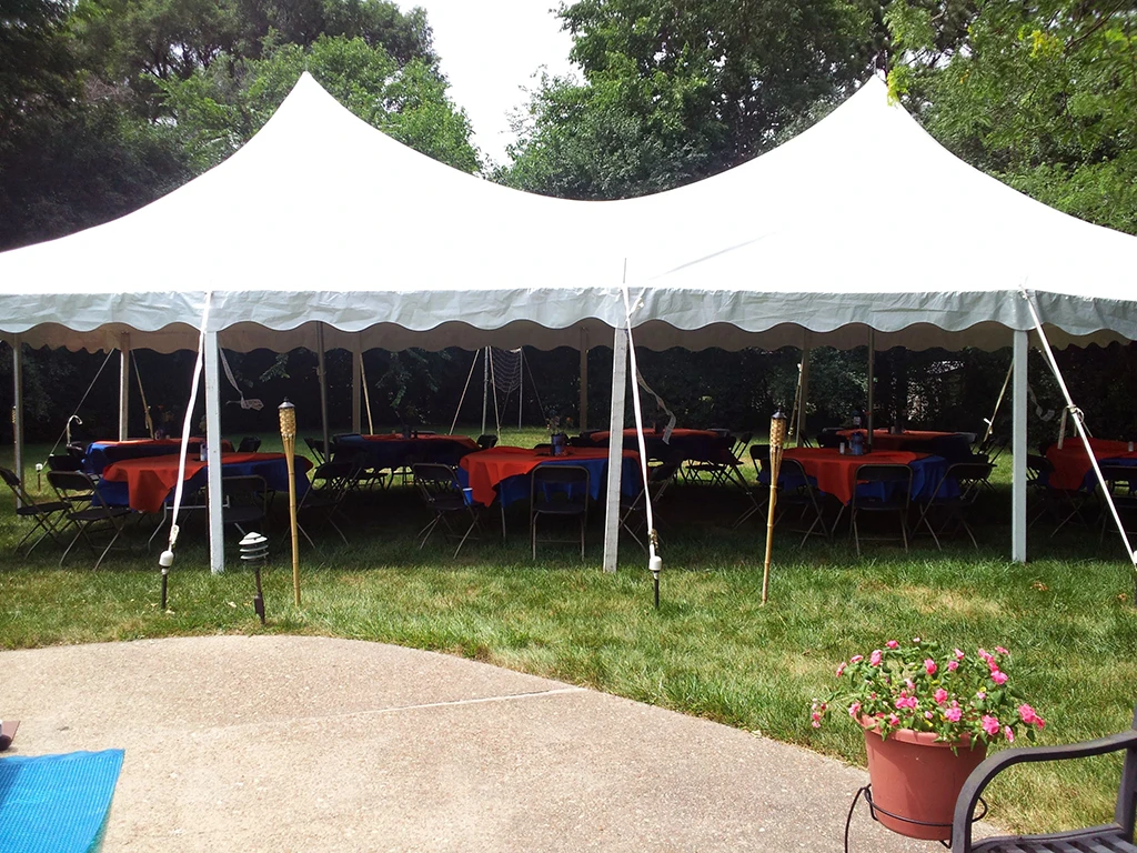 Round tables with blue and orange tablecloths under a white rental tent