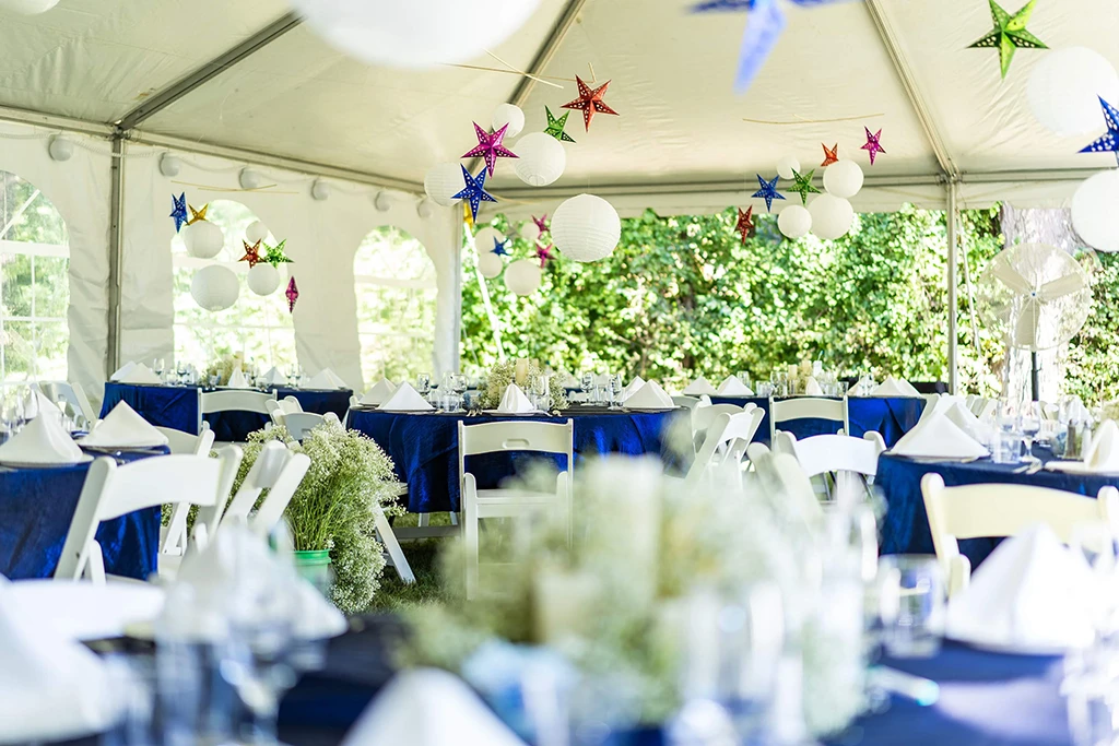 Close-up of table settings and floral decor under a rental event tent
