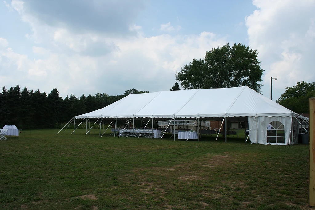 30x75 white pole tent with tables and chairs set up for an outdoor event on grass
