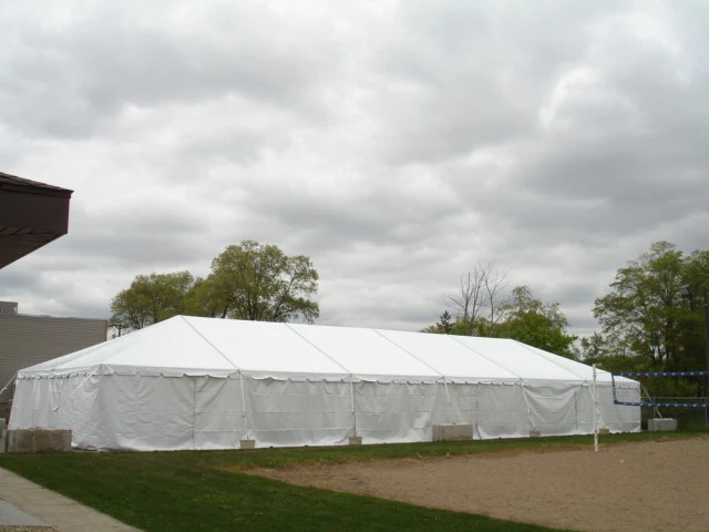 Large white tent set up next to a volleyball court under overcast skies