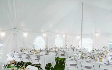 Inside view of white party tent with banquet tables and simple wedding decor