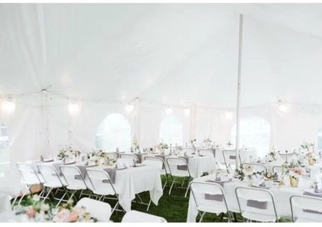 Wedding reception layout under a white tent with folding chairs and pastel centerpieces